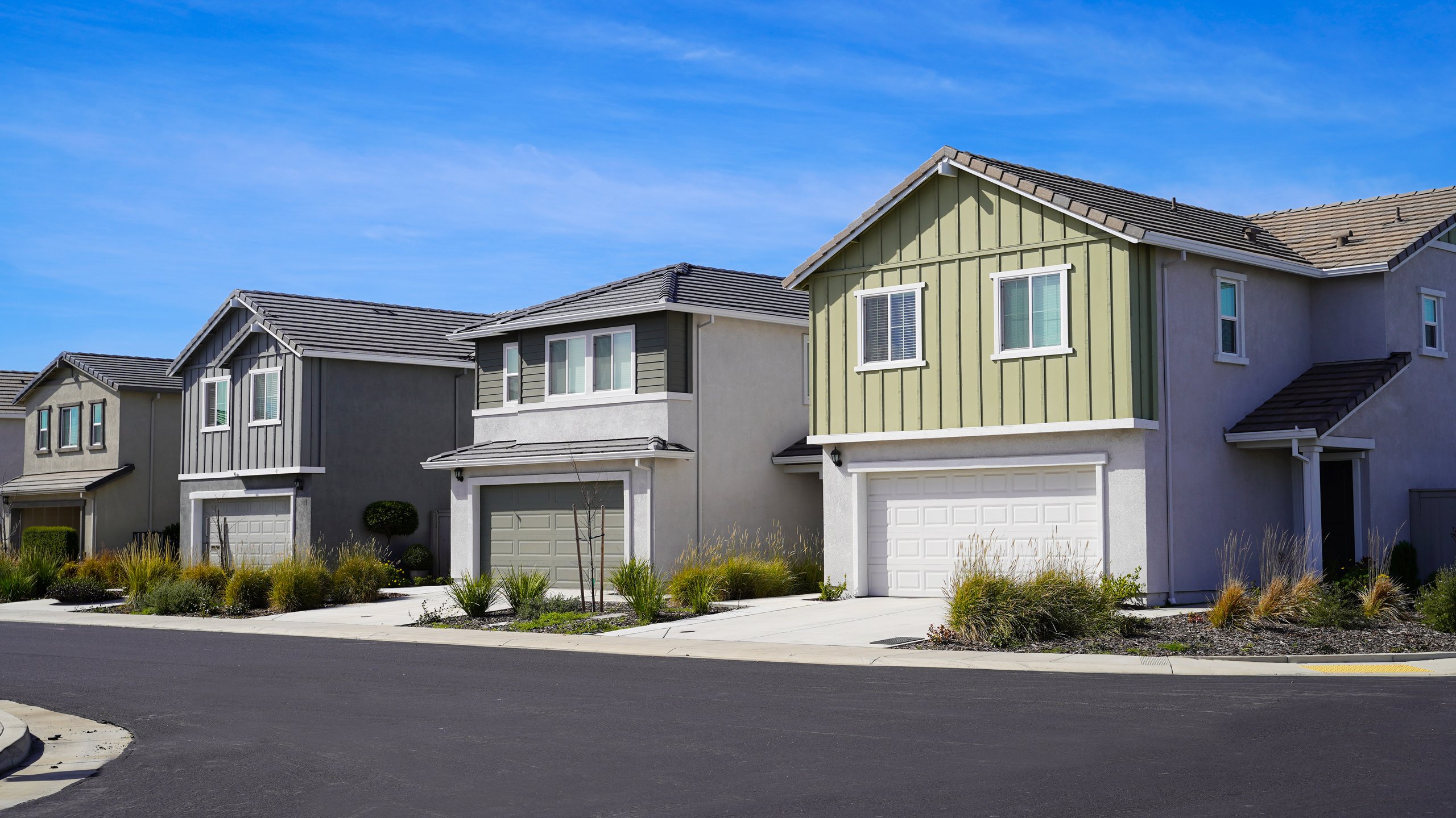 Newly built single family homes in Sacramento California with modern design, sunny blue sky, manicured lawn